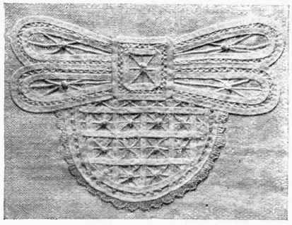 A DECORATIVE MOTIF IN WHITE BRAID WITH FANCY STITCHES.