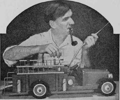 Toy  pumper  being demonstrated by Edward Thatcher, noted teacher and craftsman, who designed and built it as well as the sprinkler, tractor, and dump truck.