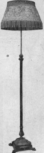 An Empire shade on an oxidised silver electric lamp. These shades are usually covered with Chine or Watteau silk, edged with a bead fringe Messrs. Shoolbred