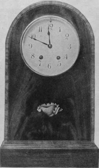 A copy of an old clock in inlaid mahogany. This wood is wax polished so as to resemble more closely the original model
