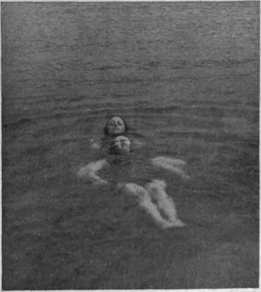 Swimming on the back, using the legs only, and towing a helpless or drowning person to shore