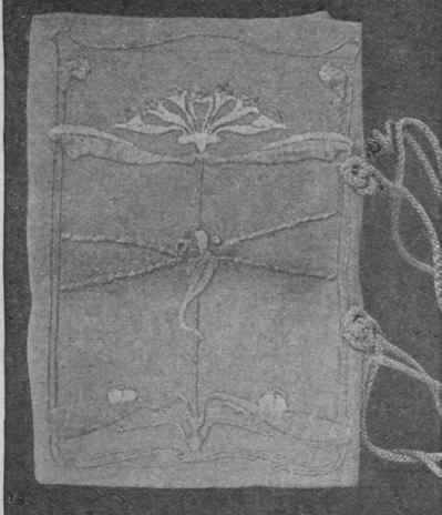 A linen book cover completed. Knotted cords and loops sewn to the front edges form a convenient handle for carrying the volume