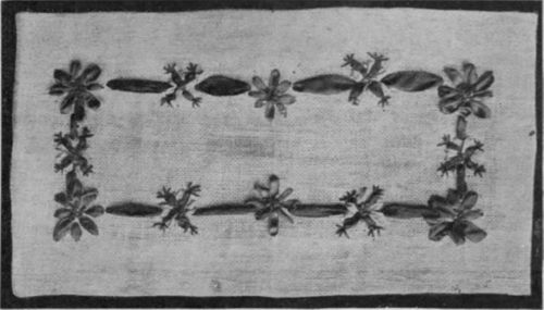 Section of table centre of canvas worked in a floral design with odds and ends of narrow ribbons and silks. Four of these sections should be joined by insertion, and the whole edged with lace to match